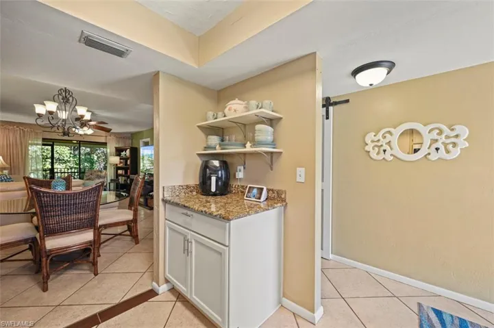 Kitchen with a barn door, stone counters, white cabinets, and light tile patterned floors