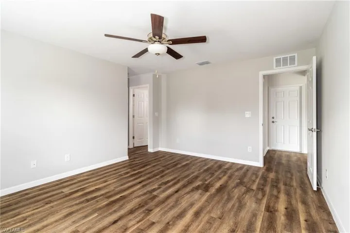 Unfurnished bedroom with dark wood-style flooring, ceiling fan, and a closet