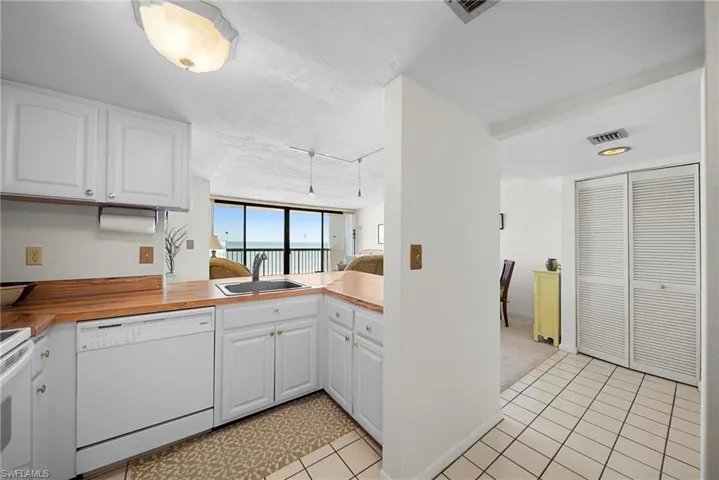 Kitchen featuring white cabinetry, white appliances, light countertops, open floor plan, and a peninsula