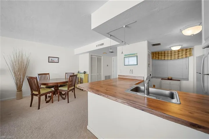 Kitchen with freestanding refrigerator, butcher block counters, a textured ceiling, light carpet, and a peninsula