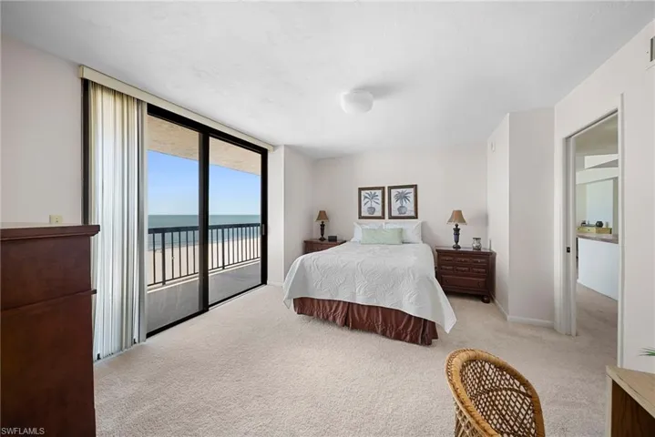 Bedroom with light colored carpet, a water view, access to exterior, and a wall of windows