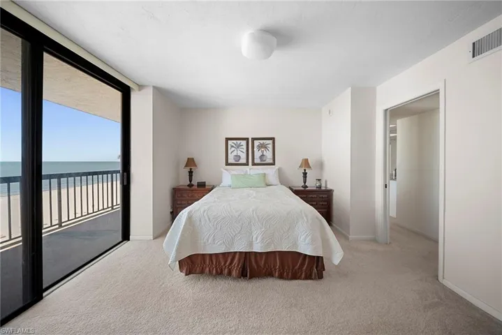 Bedroom with light carpet, access to exterior, and a water view