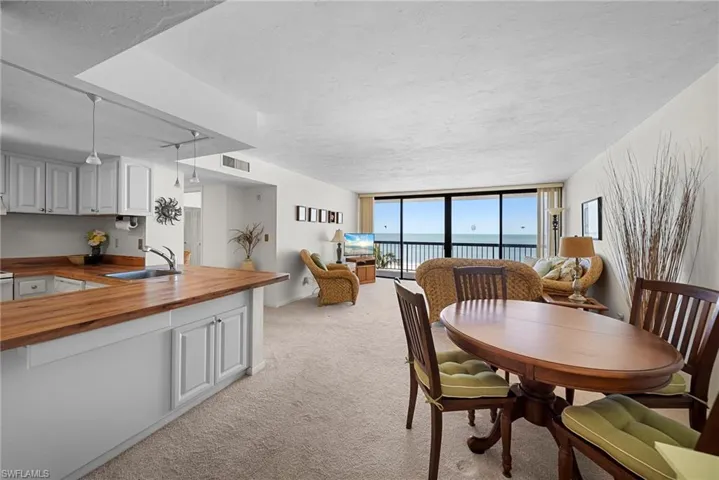 Dining space with floor to ceiling windows, light carpet, and a textured ceiling
