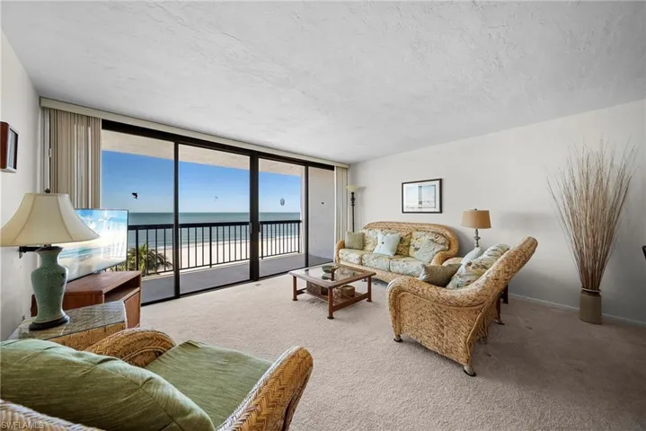 Living room featuring floor to ceiling windows, carpet floors, and a textured ceiling