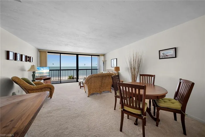 Carpeted dining area featuring a wall of windows and a textured ceiling
