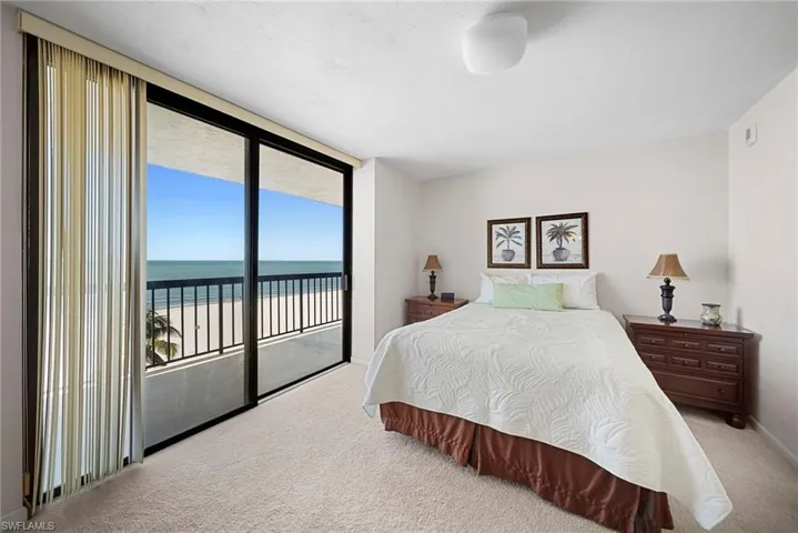 Bedroom with a water view, light colored carpet, access to outside, and floor to ceiling windows