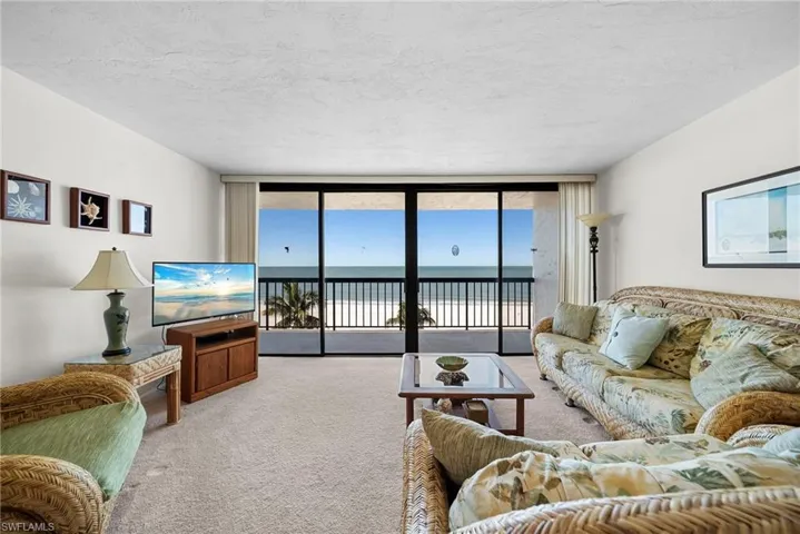 Living room featuring carpet flooring, expansive windows, and a textured ceiling