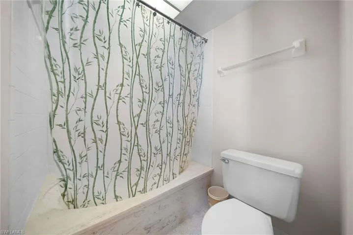 Bathroom featuring toilet and shower / bath combo with shower curtain