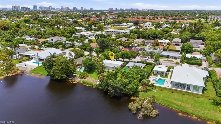 Waterfront property featuring a private swimming pool, mature landscaping, and an expansive lawn