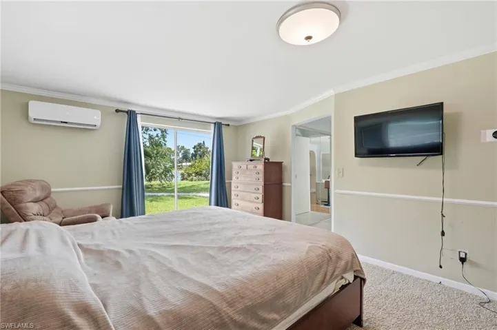 Room featuring a sliding glass door, crown molding, wall-mounted television, and a ductless mini-split system