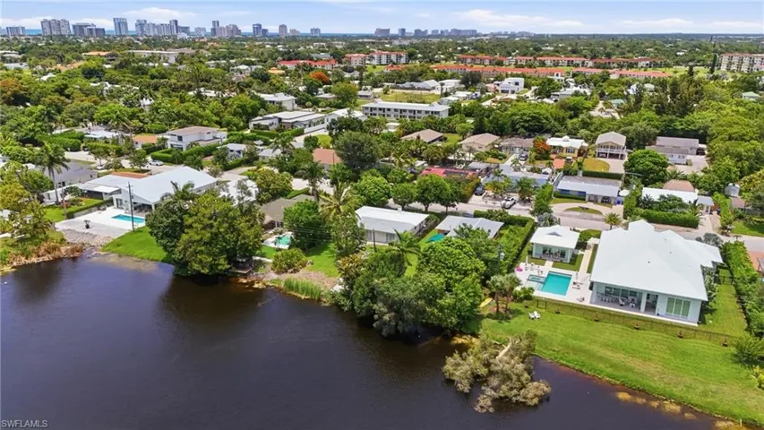 Waterfront property featuring a private swimming pool, expansive rear patio, and mature trees