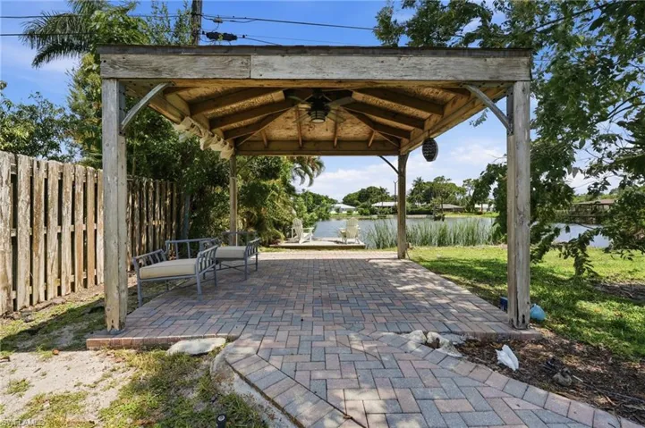 Shaded outdoor patio featuring a wood pergola structure with a ceiling fan