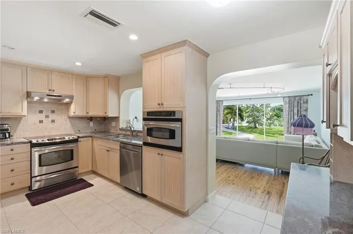 Kitchen featuring light wood cabinetry, stainless steel appliances, and tile flooring