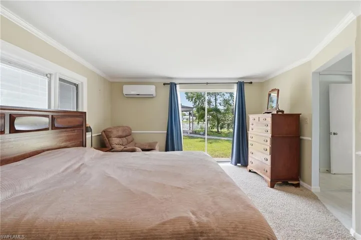 Carpeted room with a split AC unit, crown molding, and direct outdoor access through a glass sliding door