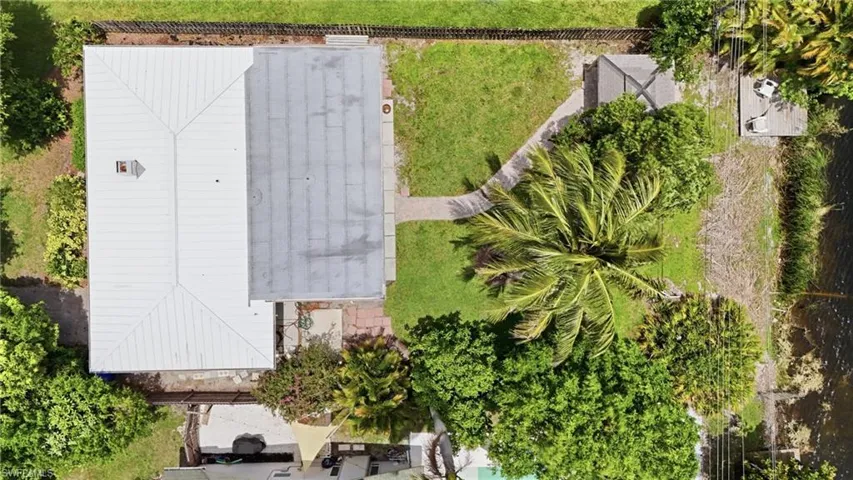 Aerial view showcasing a property with a white standing seam metal roof and a flat gray roof section