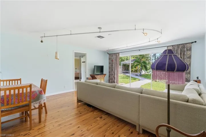 Open living area featuring wood-finish flooring, light blue wall tones, and recessed lighting on a curved track