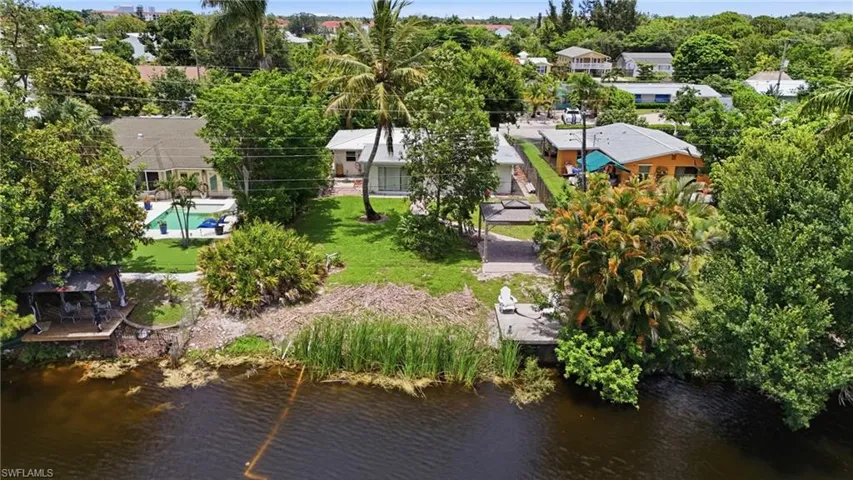 Waterfront property featuring a private boat dock, mature landscaping, and a manicured lawn