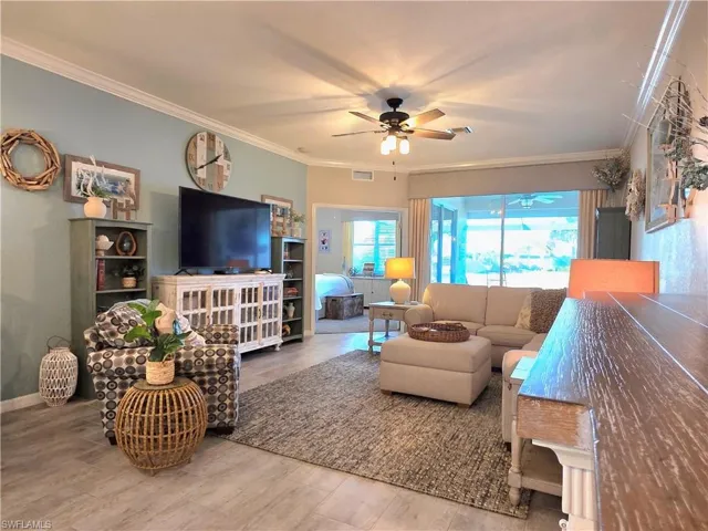 Living room featuring crown molding, wood finished floors, and ceiling fan