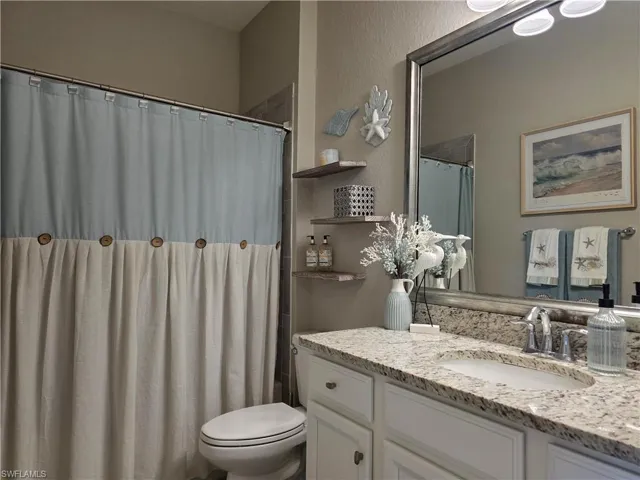 Full bath with a shower with curtain, a textured wall, and vanity