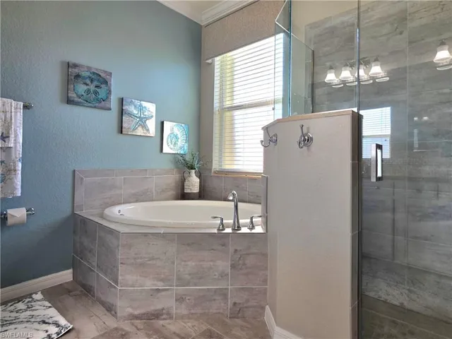 Full bathroom featuring a textured wall, a garden tub, a stall shower, and crown molding