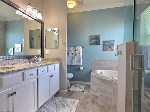 Bathroom featuring crown molding, double vanity, a bath, a textured wall, and a shower stall