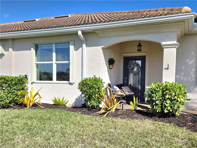 Property entrance featuring stucco siding, a lawn, and a tiled roof