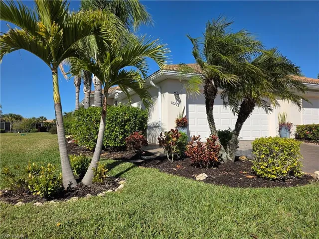 View of home's exterior with a garage, stucco siding, a yard, and driveway