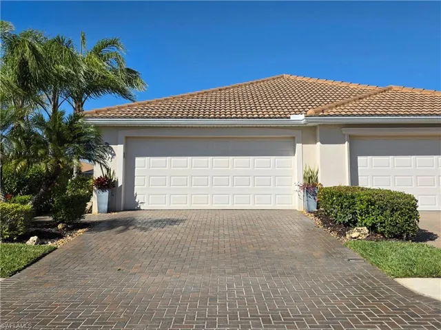 View of front of home featuring stucco siding, a tiled roof, decorative driveway, and a garage
