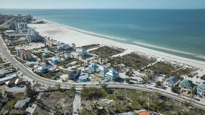 Birds eye view of property with a water view and a beach view