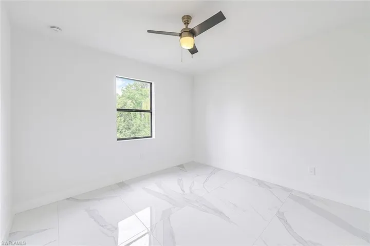 Empty room featuring light marble finish flooring and baseboards