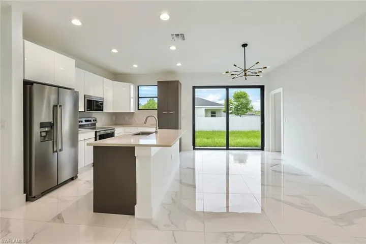 Kitchen with appliances with stainless steel finishes, white cabinets, light marble finish floors, recessed lighting, and modern cabinets