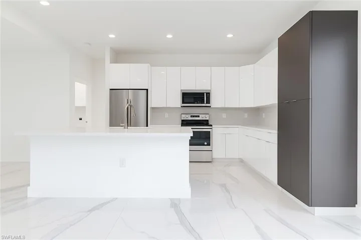 Kitchen with modern cabinets, white cabinets, recessed lighting, appliances with stainless steel finishes, and light marble finish floors
