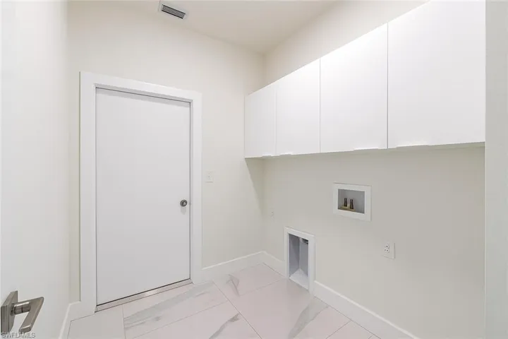 Washroom with light marble finish flooring, cabinet space, washer hookup, and an office area