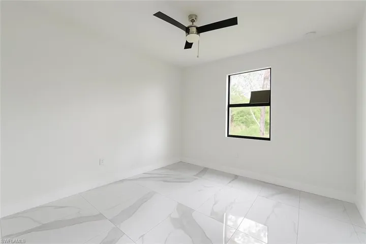 Empty room with light marble finish flooring and a ceiling fan