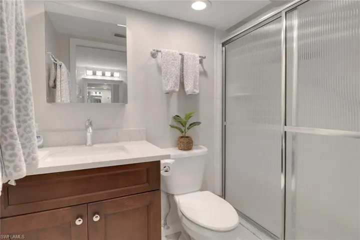 Full bath with toilet, a stall shower, visible vents, and vanity
