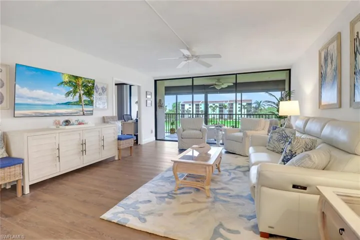 Living area featuring a ceiling fan, baseboards, floor to ceiling windows, and wood finished floors