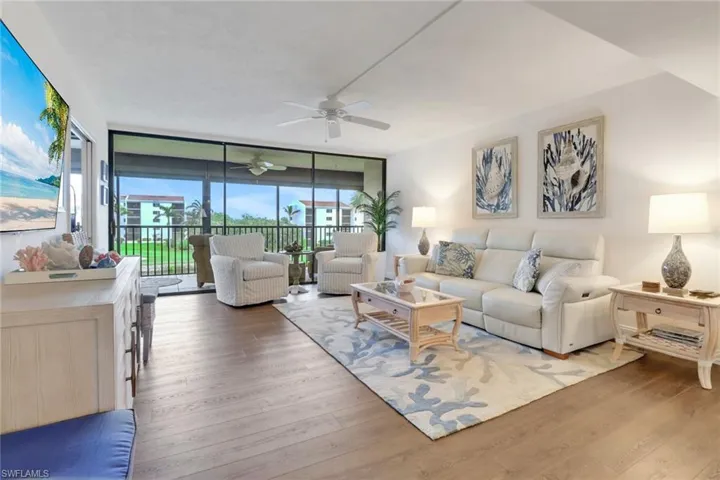 Living room featuring ceiling fan, expansive windows, and wood finished floors