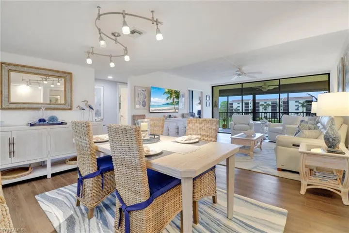 Dining room with ceiling fan, visible vents, a wall of windows, and wood finished floors