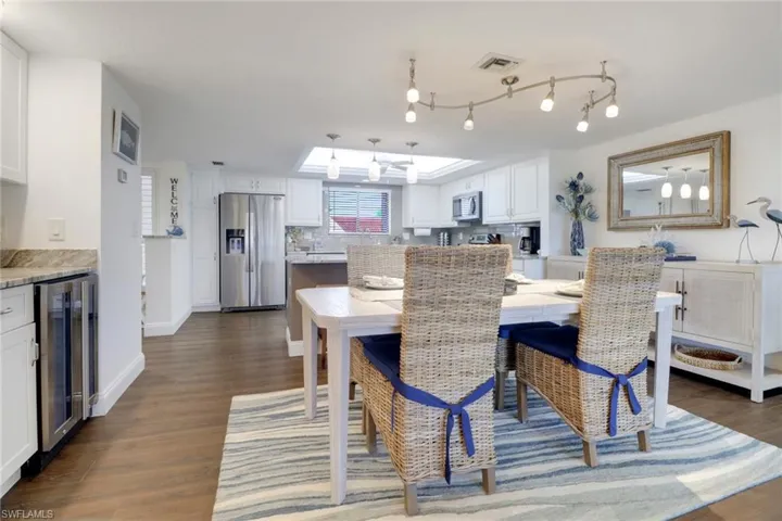 Dining room with wine cooler, dark wood-style flooring, visible vents, and baseboards