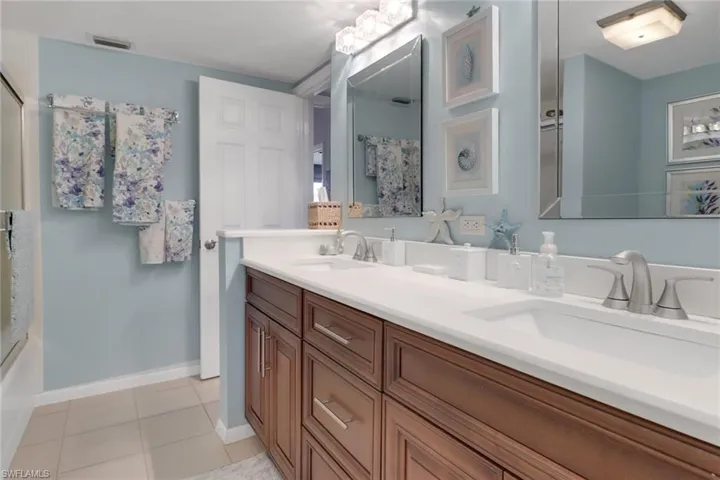 Bathroom with tile patterned flooring, visible vents, a sink, and double vanity