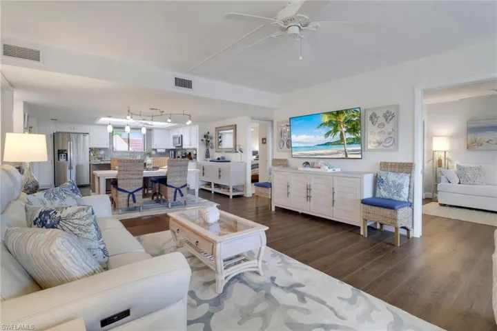Living area with dark wood finished floors, visible vents, and a ceiling fan