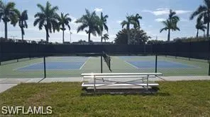 View of tennis court featuring fence and a lawn