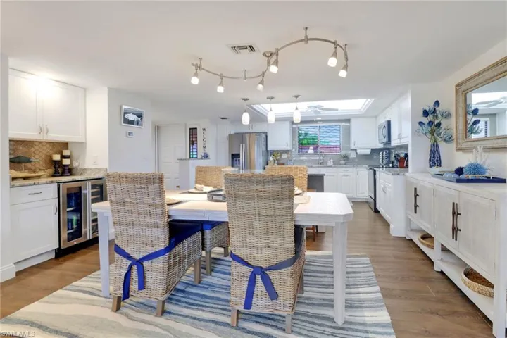 Dining area with wine cooler, visible vents, and wood finished floors