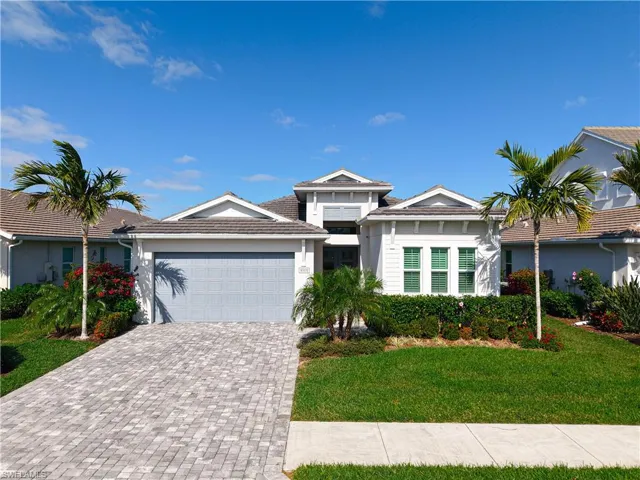 View of front facade featuring an attached garage, a tile roof, decorative driveway, stucco siding, and a front yard
