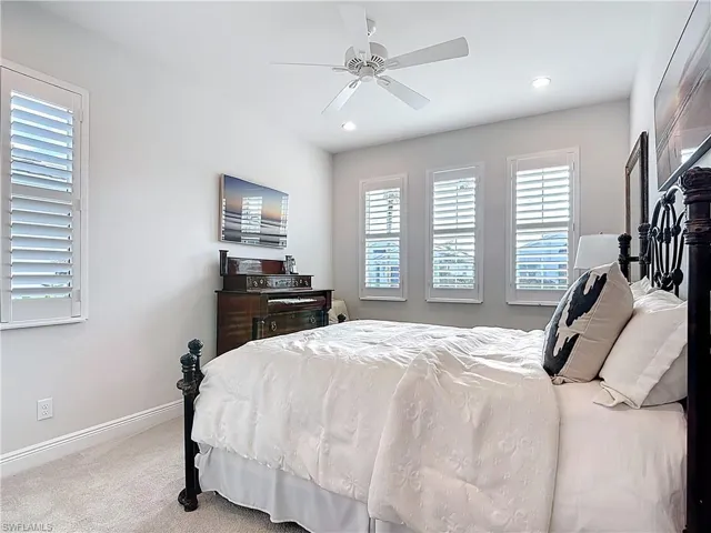Expanded carpeted guest bedroom with double wood shelf closet and recessed lighting.