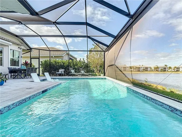Outdoor pool featuring glass enclosure, a patio area, and a water view