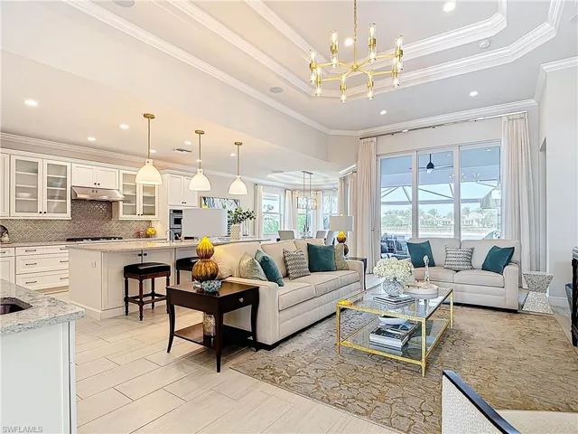 Living area featuring recessed lighting, a raised ceiling, light wood-style flooring, an inviting chandelier, and ornamental molding