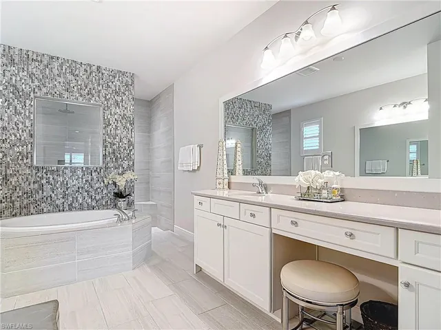 Full bath featuring duel vanities,  custom tiled shower wall and soaking tub.