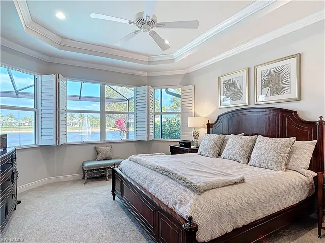 Bedroom with light carpet, coffered ceiling, crown molding, door to lanai and expansive lake views.