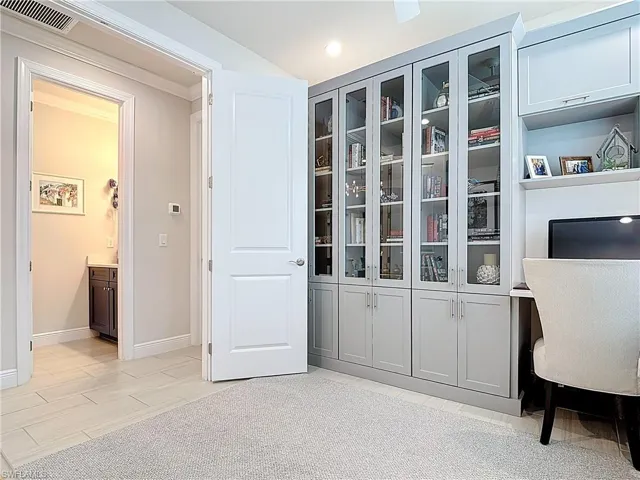 Home office with double doors, recessed lighting, glass door bookcases and storage cabinets.